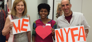 Three individuals with "We (Heart) NYFA" signs