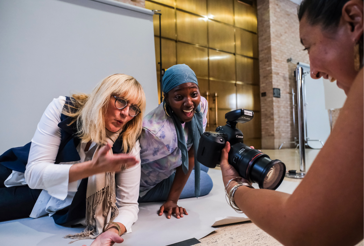 Two women leaning in to view the digital screen on the back of a camera to see the photo that was just taken of them.