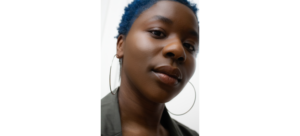 Aliyah Curry headshot; a Black woman with short blue hair looks into the camera from an above angle.