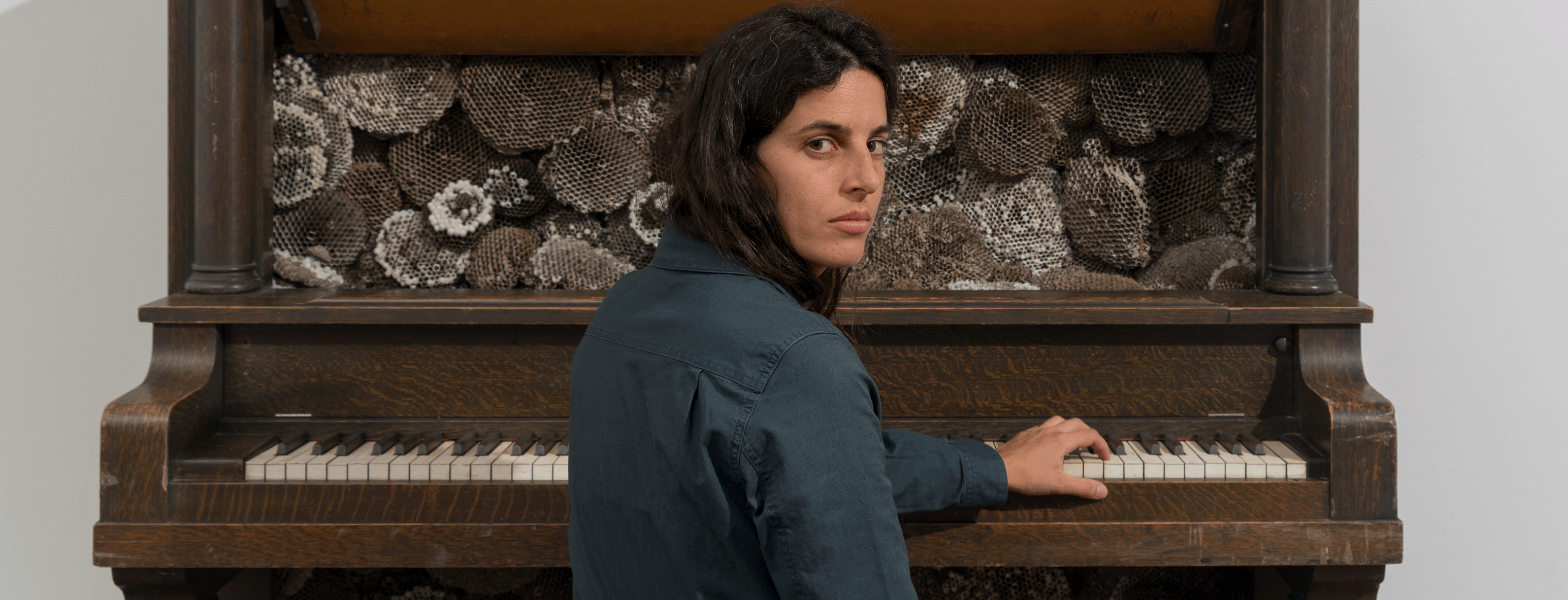 2025 Vilcek Foundation Prize Recipient Selva Aparicio is seated at a piano whose interior is filled with dried honeycomb.