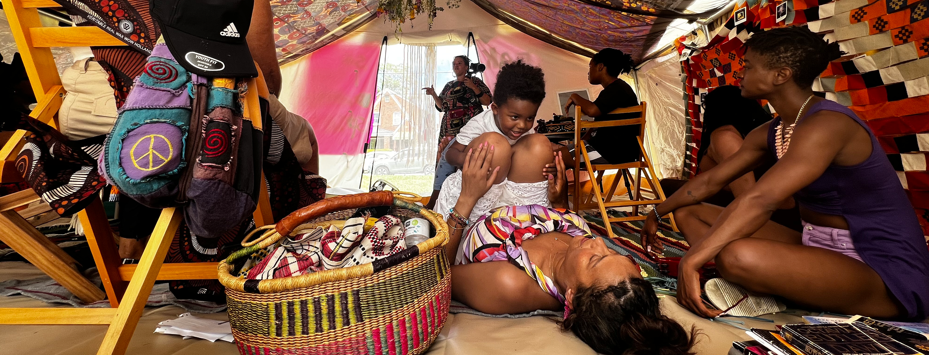 Individuals interact in a colorful, tent-like setting, part of Alisha B Wormsley's open-to-the-public filming in Pittsburgh, PA.