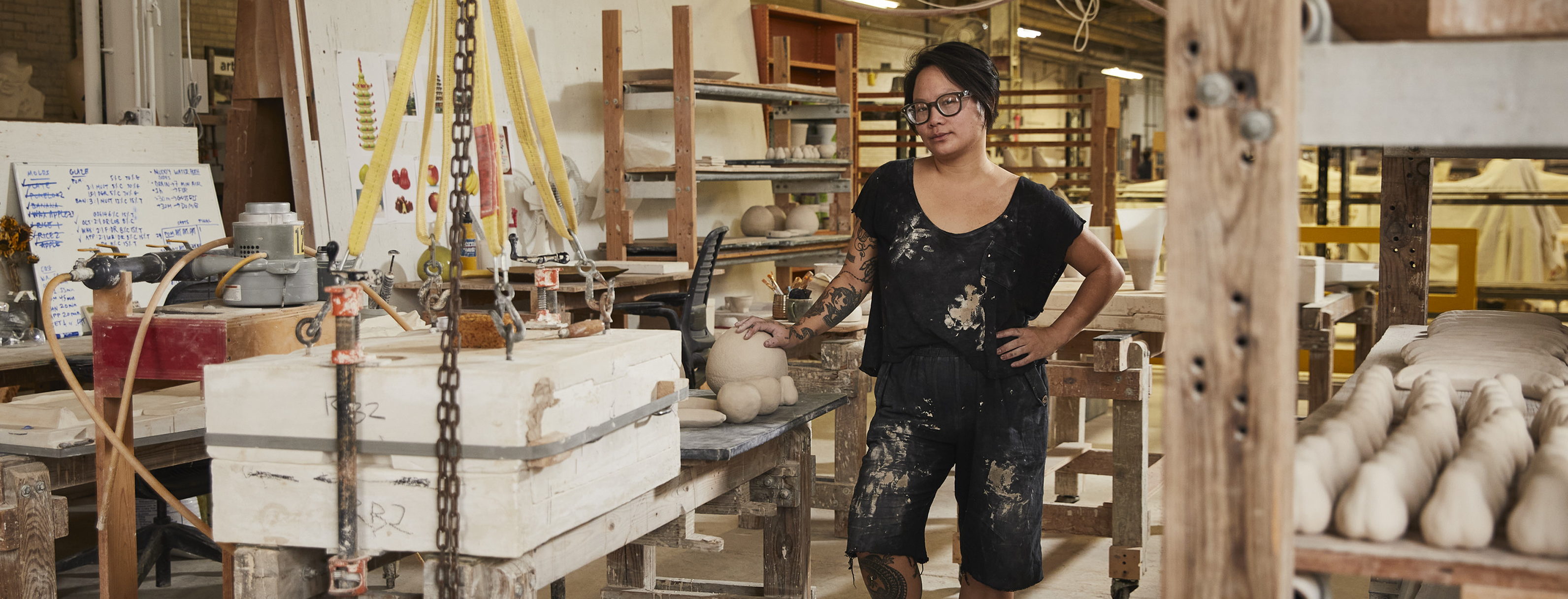 Stephanie H. Shih at in a studio setting, with ceramics and a giant slip mold nearby